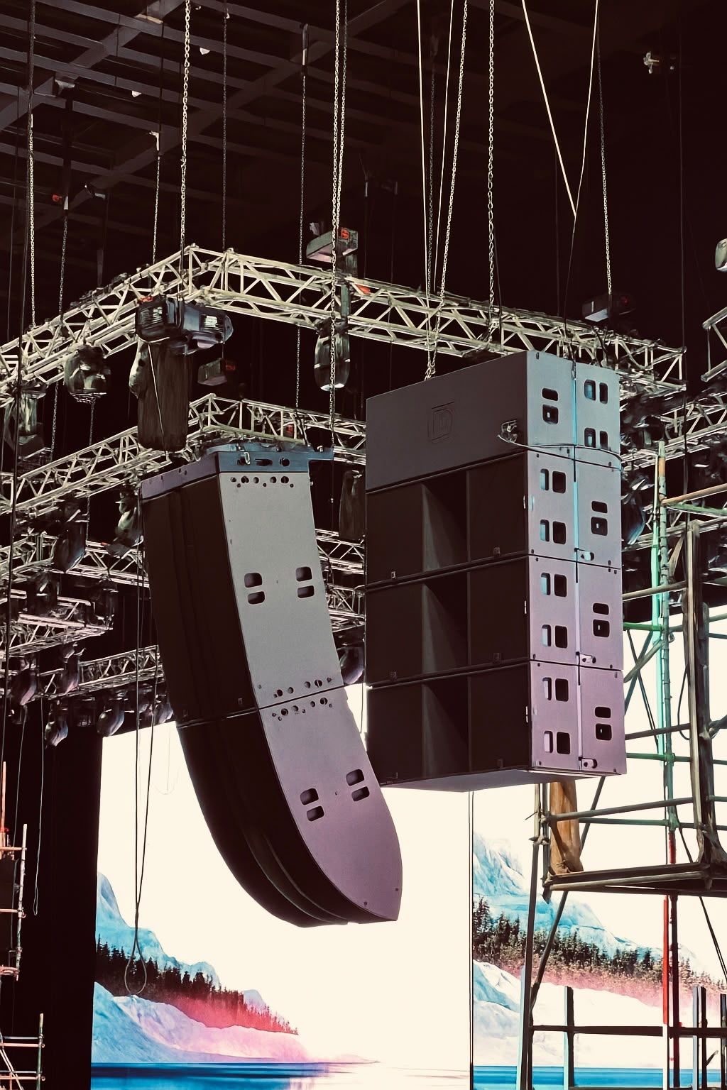 Line arrays flown from truss above a video wall