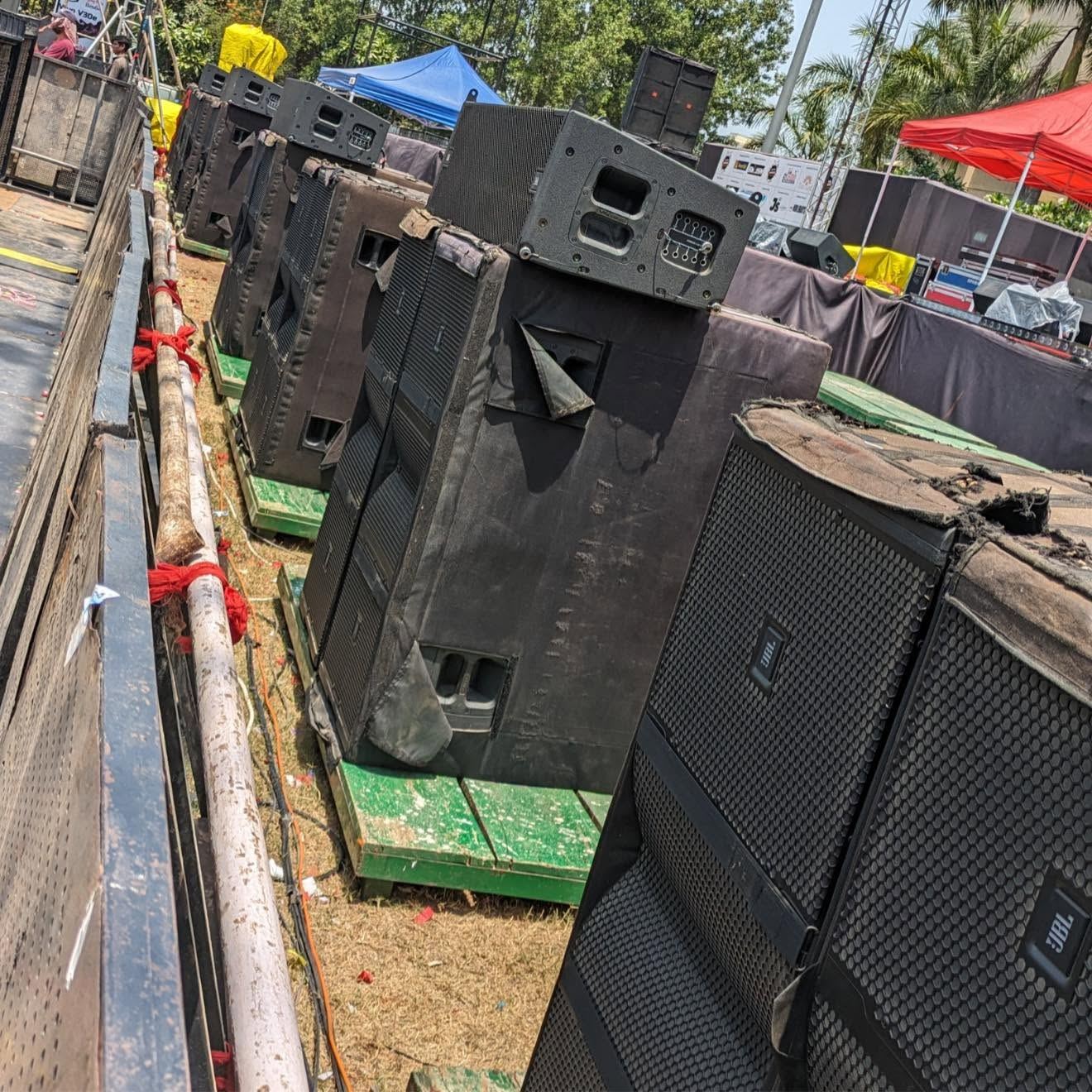 Row of ground-stacked speakers on pallets at an outdoor event