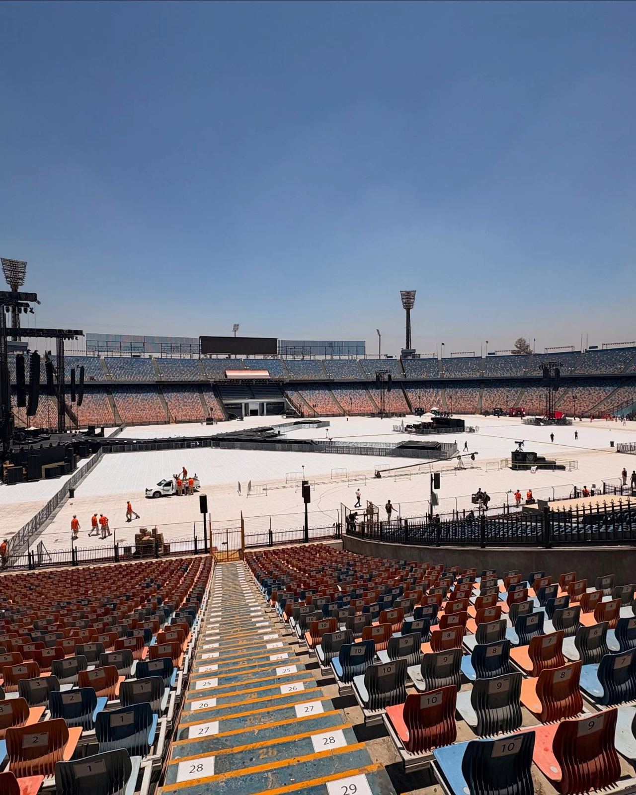 Empty stadium during setup seen from the stands, with delay towers on the field