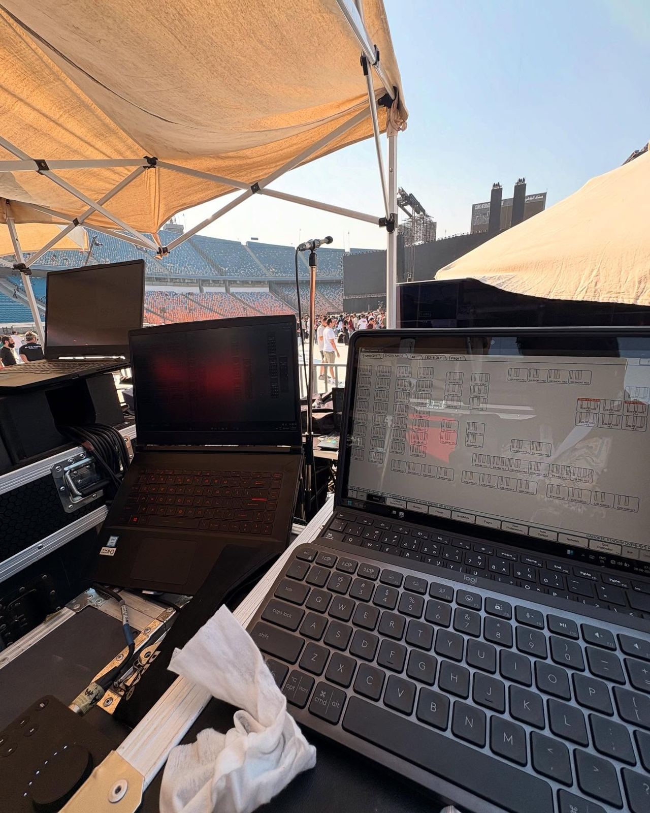 System engineering laptops under a shade tent overlooking a stadium